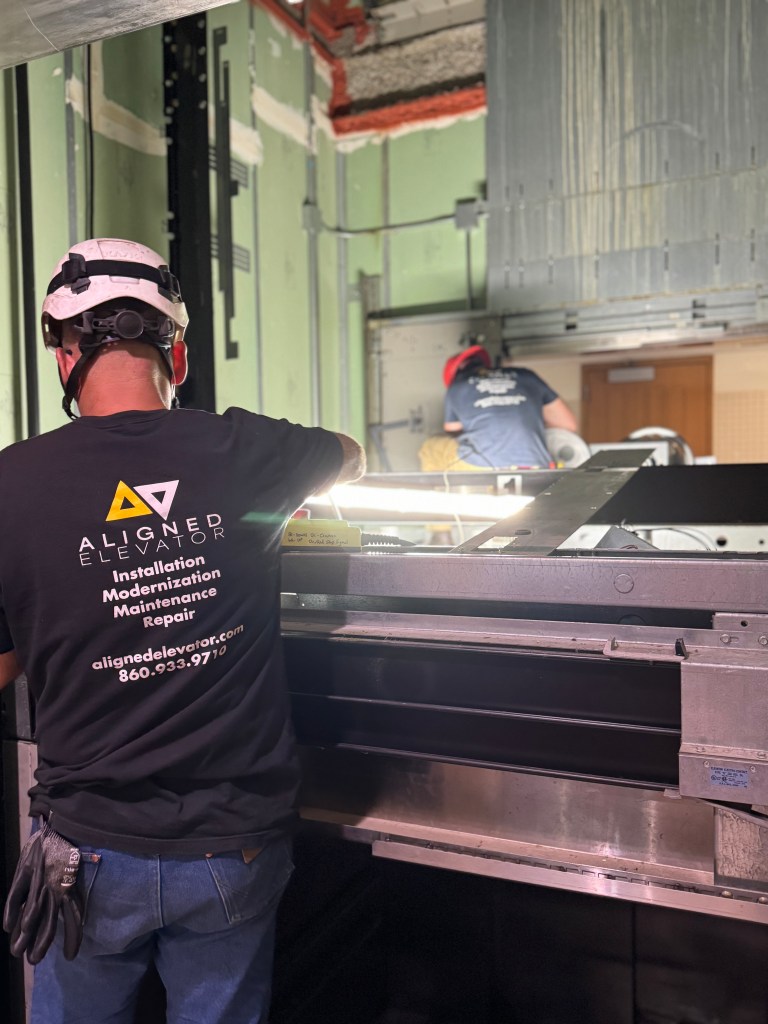 Aligned Elevator technician repairing an elevator in Connecticut